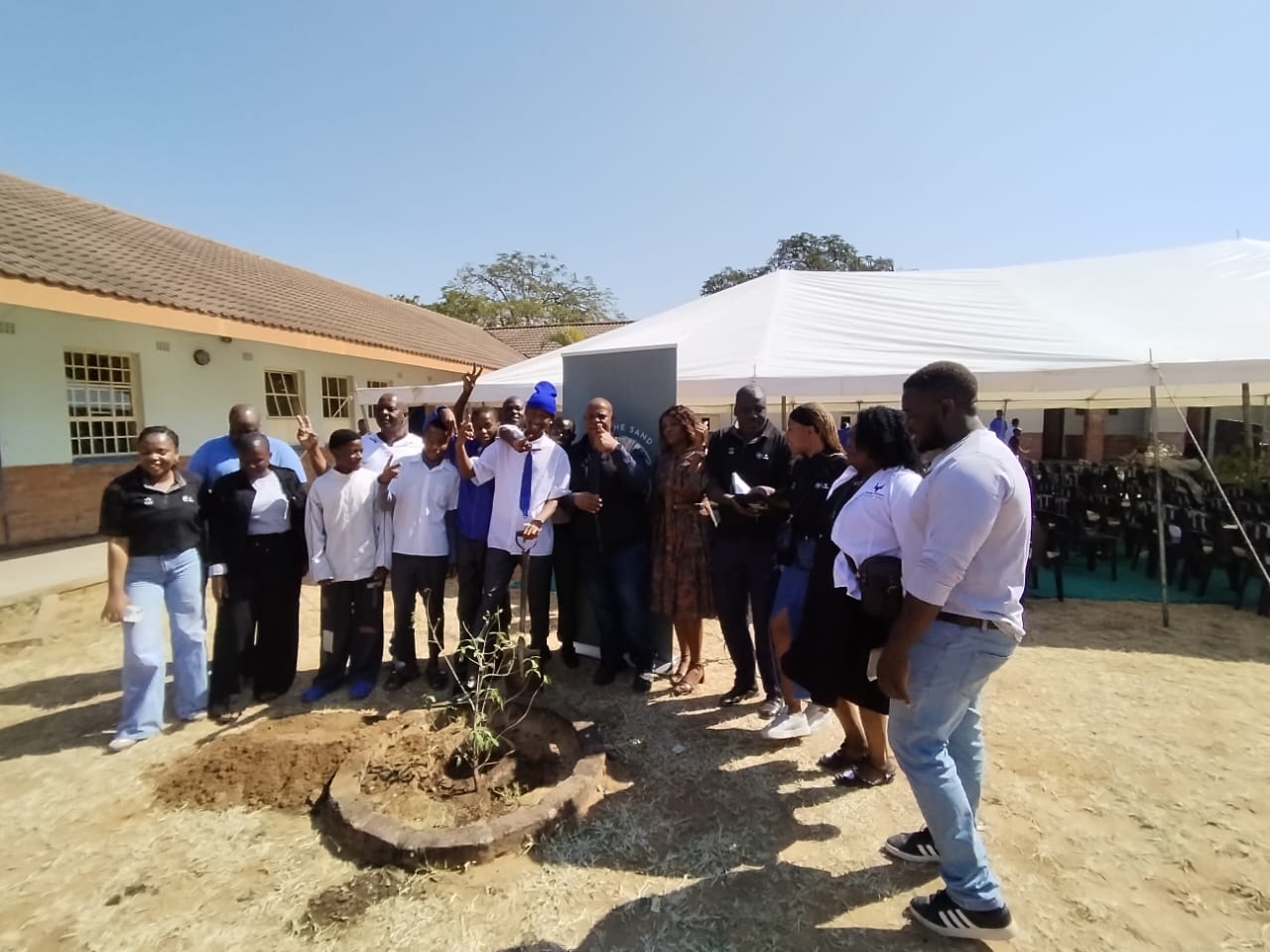 Group around the newly planted school tree at the close of the day.