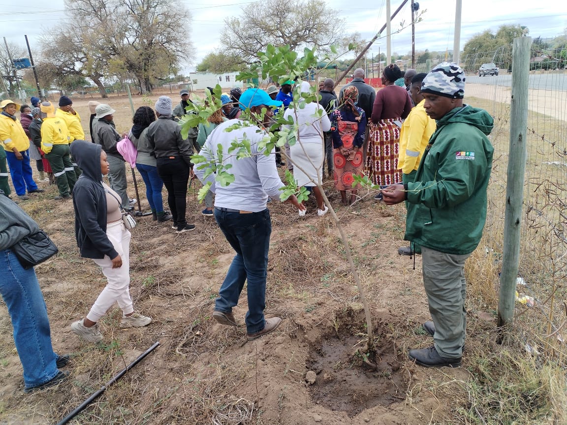 Community members at the river bridge, clearing waste from a dumping site.