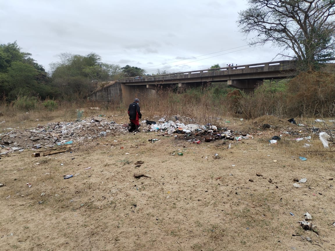 A stretch of riverbank piled with rubbish, ready for clearing.