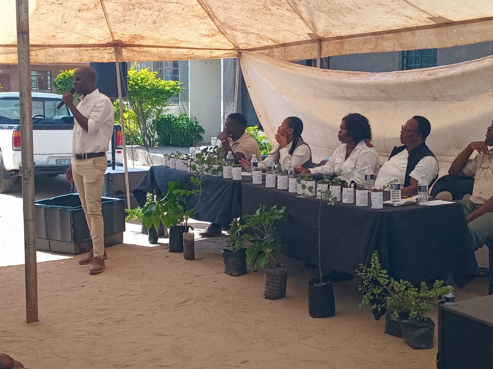 School awareness session, panel of speakers under a tent.
