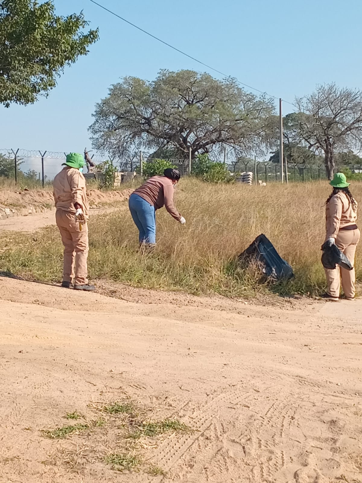 Volunteers picking up waste along a village track.