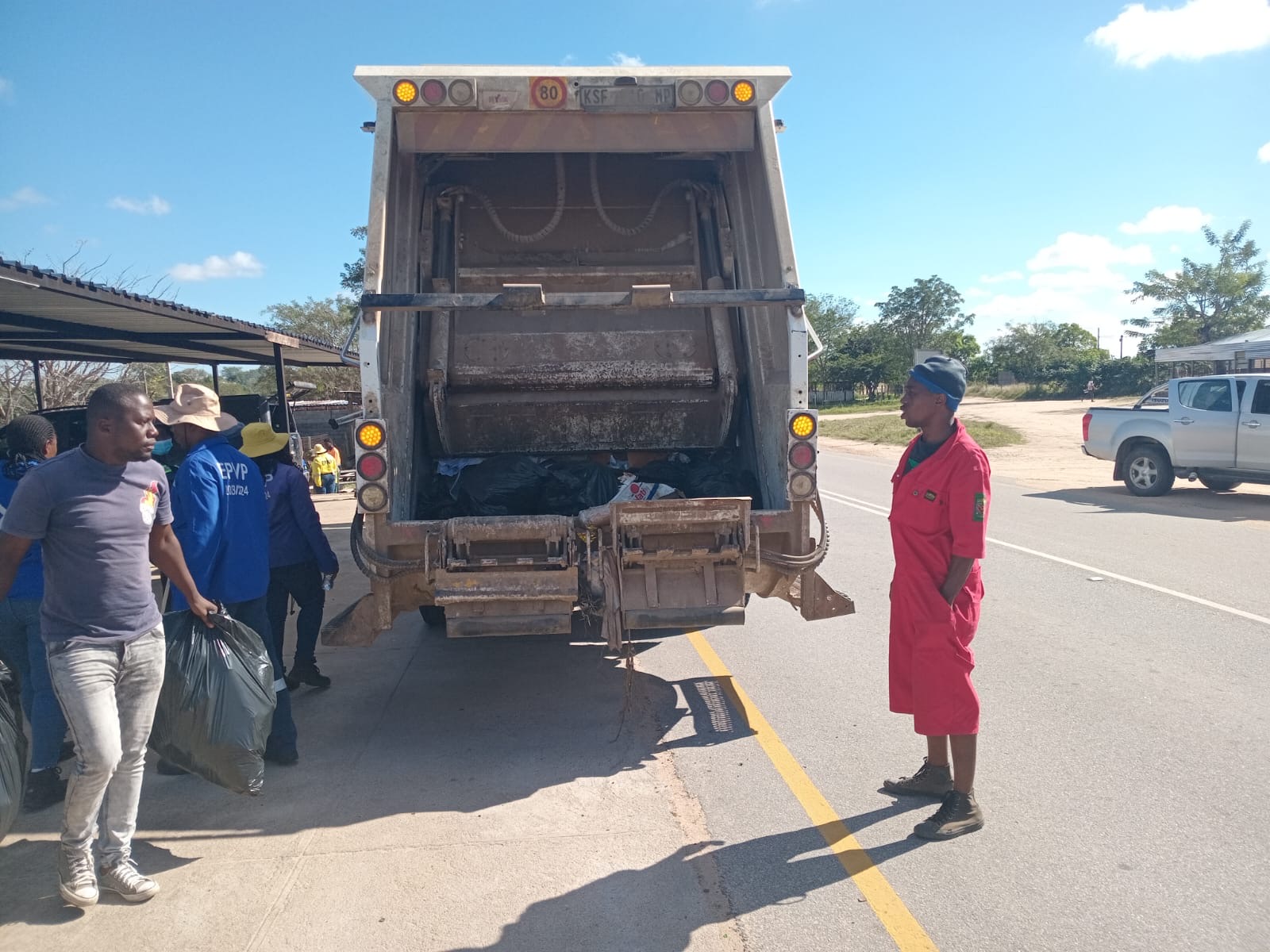 A municipal waste compactor truck collecting bags during the river day.