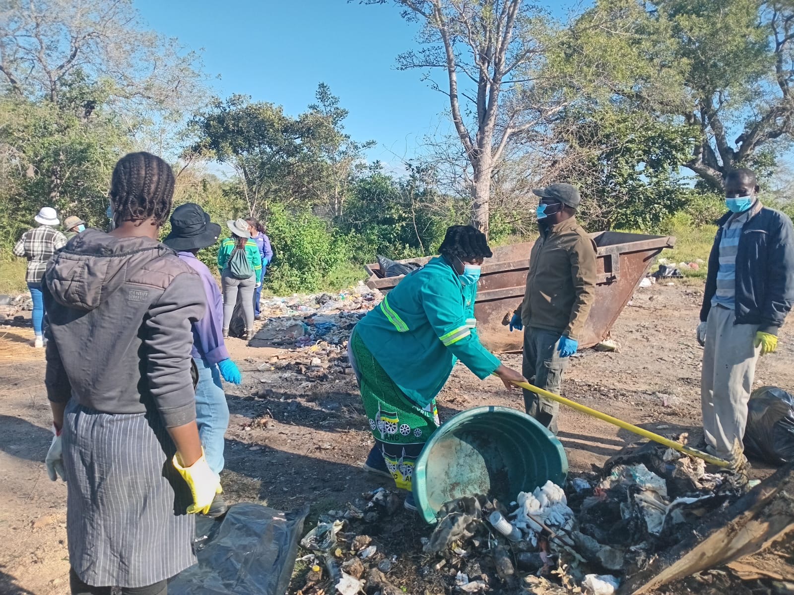A volunteer scooping waste into a wheelbarrow at the dumping site.