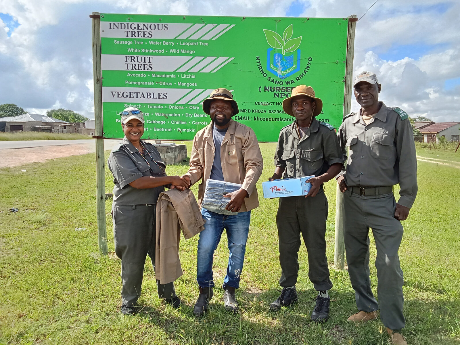 Project team and nursery operators stand together in front of the Ntirhisano Wa Rihanyi signboard at Lillydale during a handover of PPE and supplies.